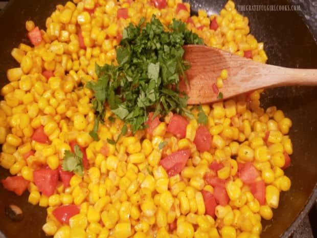 Chopped cilantro is added to the hot corn in the skillet, before serving.