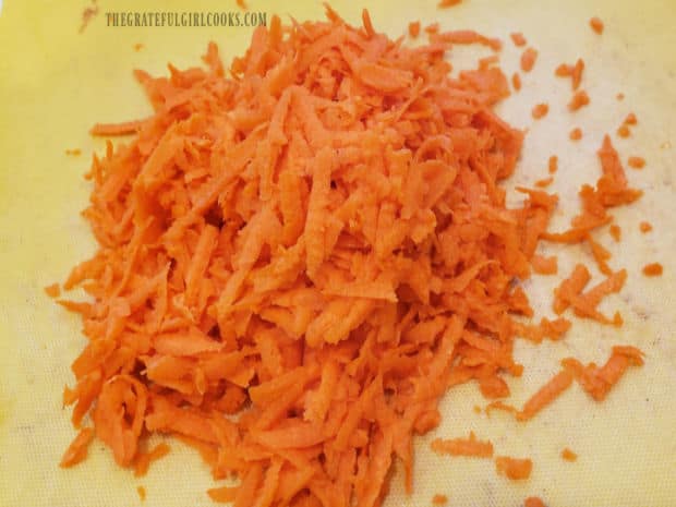 Two carrots are shredded to use in the zucchini carrot lime coleslaw.