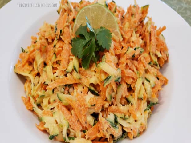 Zucchini Carrot Lime Coleslaw is garnished with lime wedge and cilantro sprigs to serve.