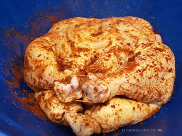 Chicken legs are tied together, and chicken is covered with spice mixture before cooking.