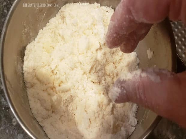 Cold butter, flour and sugar are rubbed together to form coarse crumbs in bowl.