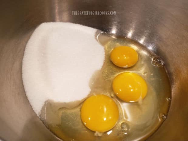 Three eggs and granulated sugar are placed in mixing bowl.