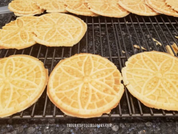 Classic pizzelle cookies cooling on wire rack after being removed from machine after cooking.