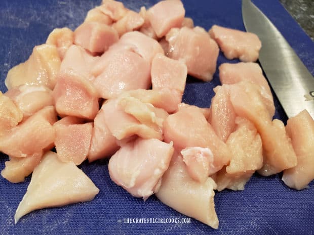 Boneless, skinless chicken breasts are cut into bite-sized cubes.