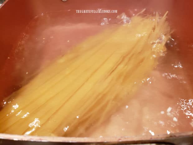 Spaghetti noodles are cooked in boiling water per package instructions.