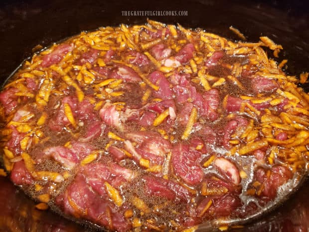 Strips of beef are added to the crock pot with sauce and cooked several hours until tender.