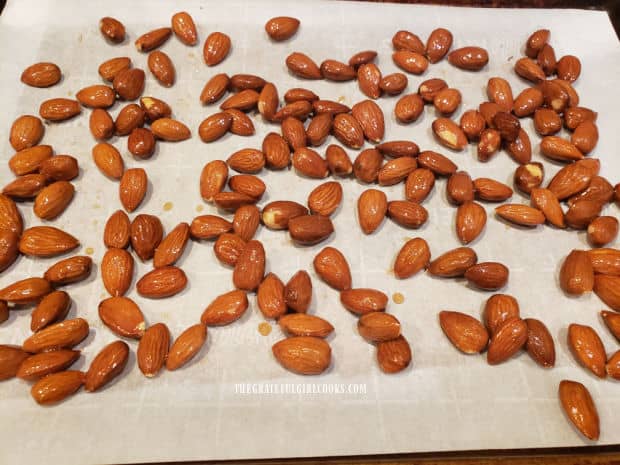 Almonds are placed in a single layer on a parchment paper-lined baking sheet for roasting.