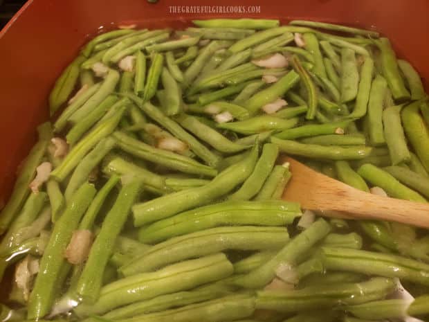 Green beans and bacon are cooked in boiling water for 5 minutes.