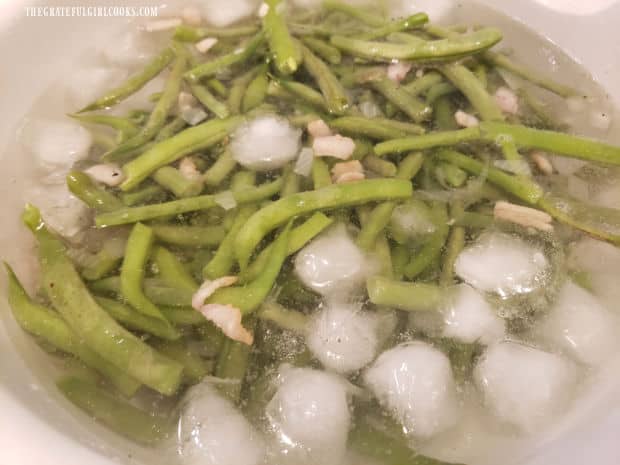 Immediately after cooking, the green beans are immersed in ice water to stop the cooking.