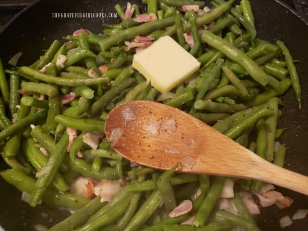 Butter is added to the green beans in the skillet.