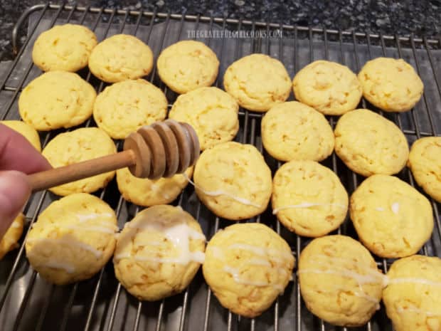 A honey dipper is used to drizzle lemon glaze over the cookies.