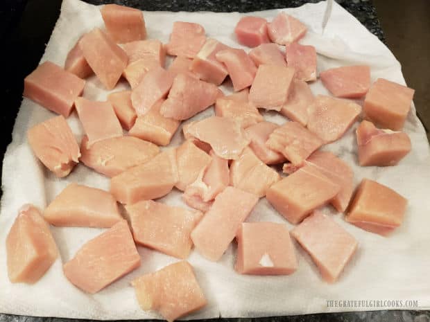 Chicken breasts are cut into cubes, then dried on paper towels before cooking.