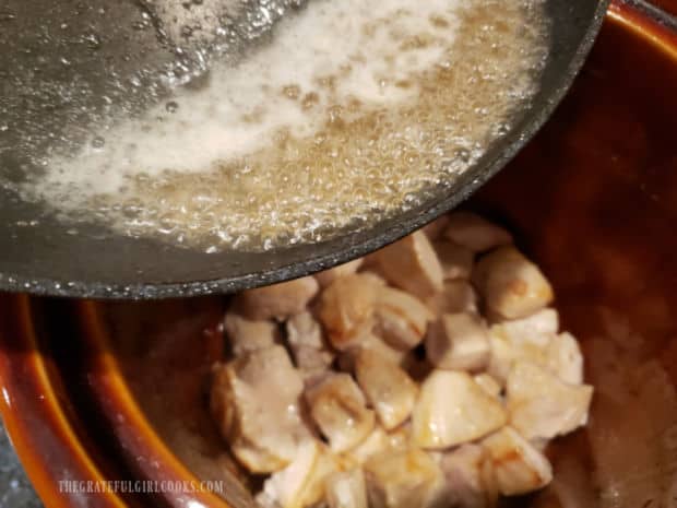 Water and pan drippings are poured onto the browned chicken pieces in crock pot.