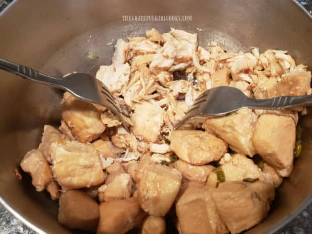 Two forks are used to pull apart the Mexican shredded chicken after it has been fully cooked.