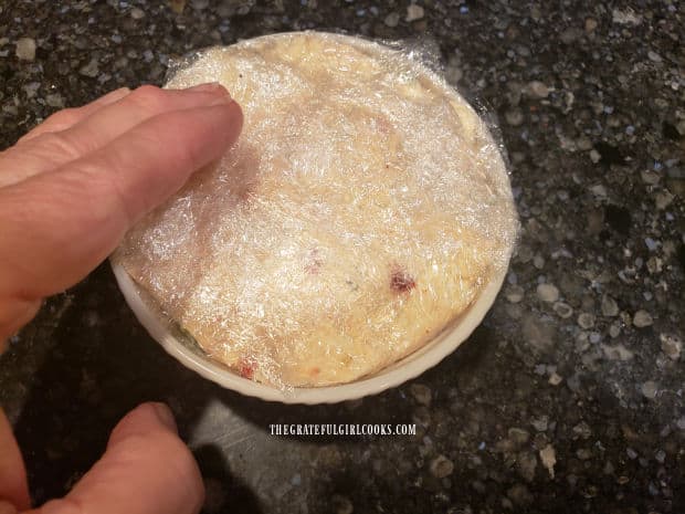 Covered with plastic and pressure applied, the cheese ball is ready for the refrigerator.