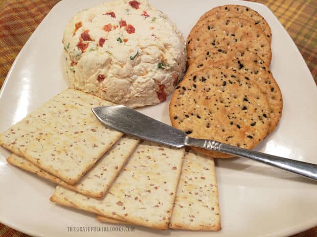 Parmesan garlic cheese ball on a plate, ready to be spread on crackers.