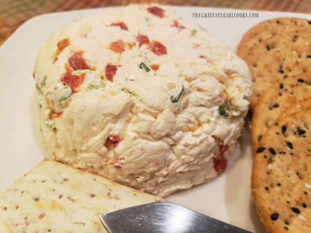A close up of the Parmesan garlic cheese ball next to crackers on a plate.