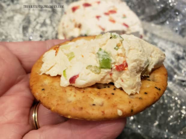 The Parmesan garlic cheese ball is spread onto a cracker for eating.