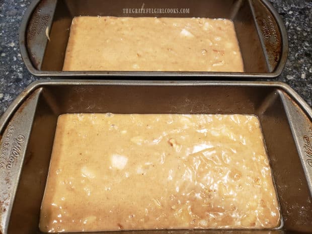 Bread batter is poured evenly into two greased loaf pans before baking.