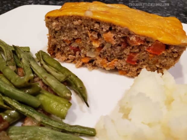 A slice of the TexMex turkey meatloaf, served on a plate with potatoes and green beans.