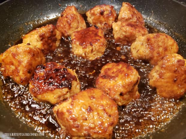 Sauce is added to cooked chicken meatballs in skillet and cooked until it thickens.