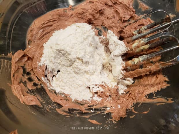 All purpose flour is gradually beaten into the cookie dough mixture in the bowl.