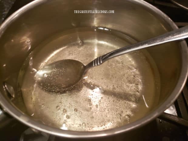 Sugar, oil, and vinegar are boiled in saucepan to begin making the French salad dressing.