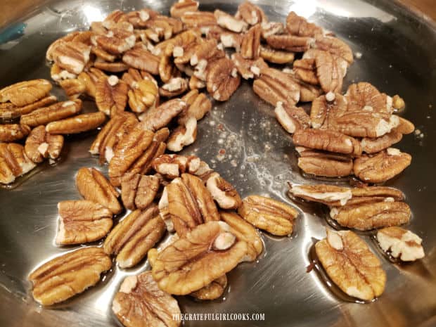 Pecan halves are lightly toasted in a skillet with hot oil.