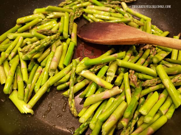 Asparagus pieces are cooked in olive oil for 3-4 minutes in a large skillet.