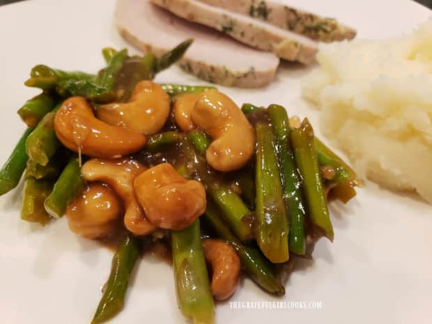 Sliced pork loin and mashed potatoes are served with the asparagus cashew stir fry.