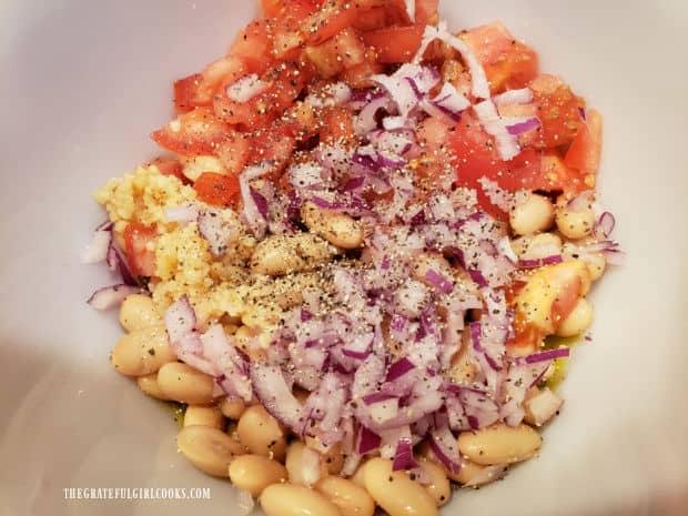 All the ingredients for the cannellini bean salad are combined in a bowl.