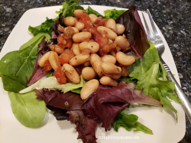 Cannellini bean salad is served as a topper for a mixed green salad.