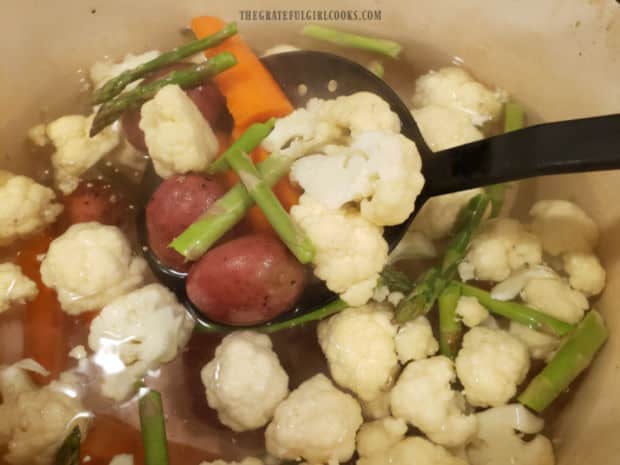 Cauliflower florets, carrots, asparagus and red potatoes are par-boiled in water until tender.