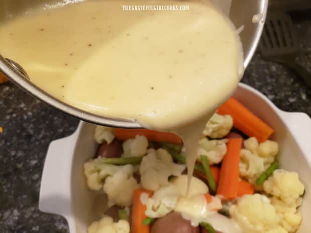 Cheese sauce is poured over the top of the veggies in the baking dish, to cover.