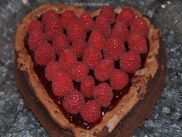 The surface of the chocolate raspberry torte is covered with fresh raspberries.