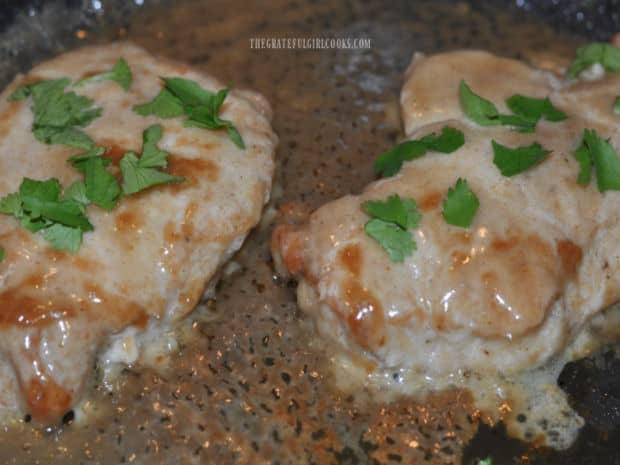 Chopped flat leaf parsley is sprinkled on top of the Creamy Honey Dijon Pork Chops before serving.