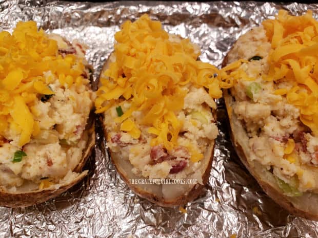 The double stuffed potatoes are topped with grated cheese before baking.