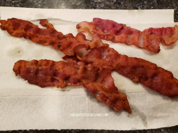 Crispy bacon is cooled on paper towels, then crumbled into small pieces.