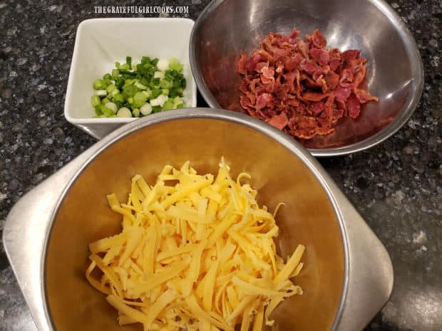 Chopped green onions, bacon crumbles and grated cheddar are ready to add to potatoes.