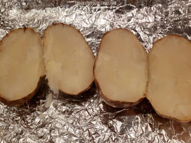 Hot baked potatoes are sliced in half before scooping out the insides.