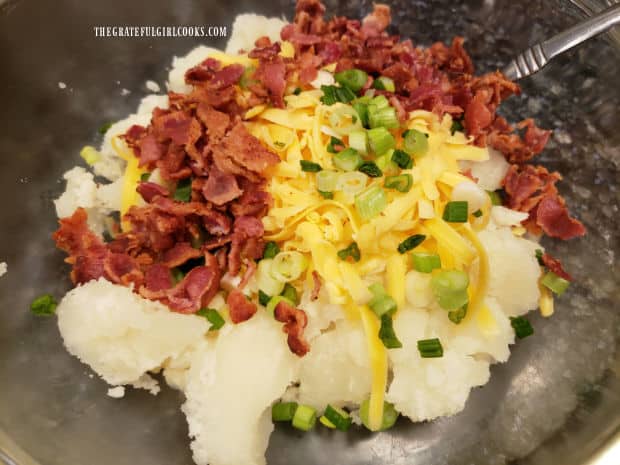 Crisp bacon crumbles, green onions, and grated cheese are added to the cooked potato.