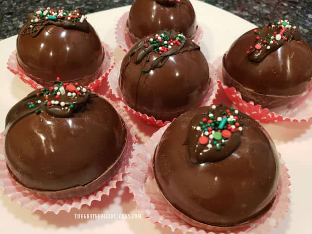 Decorated hot cocoa bombs are placed in cupcake papers until ready to serve. 