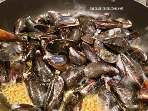 Mussels are added to the skillet with white wine, shallots and garlic.