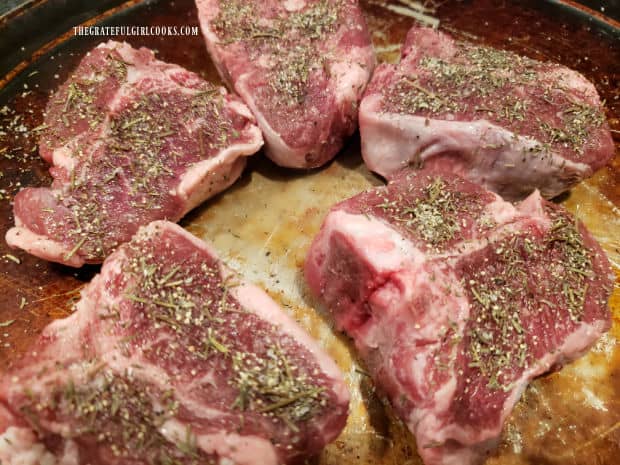 Lamb chops are seasoned with spices on both sides before cooking.