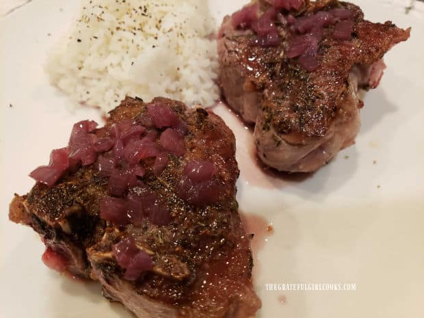 Two rosemary wine lamb chops are served on a plate with rice on the side.