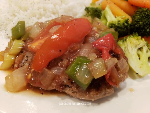 One of the smothered turkey patties topped with sauce and veggies, served with rice on the side.