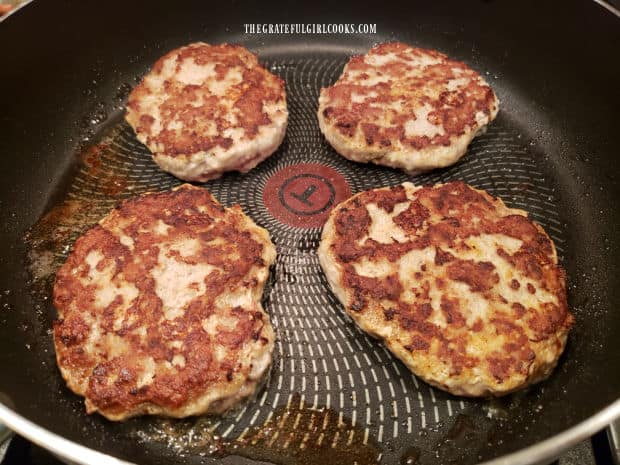 After searing the bottom of the turkey patties, they are flipped to cook the other side.