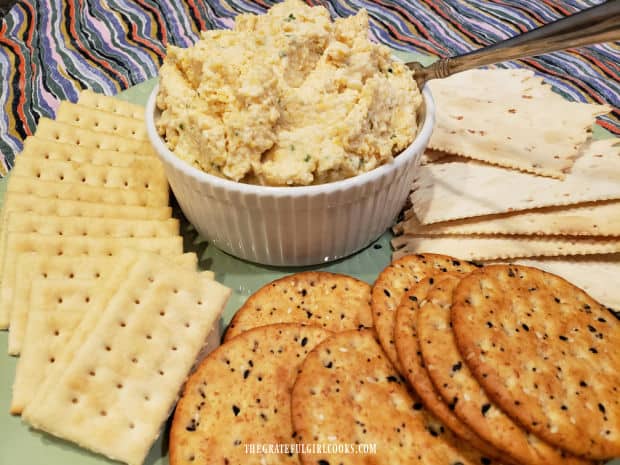A ramekin, filled with cheddar jack cheese spread, is served with assorted crackers.