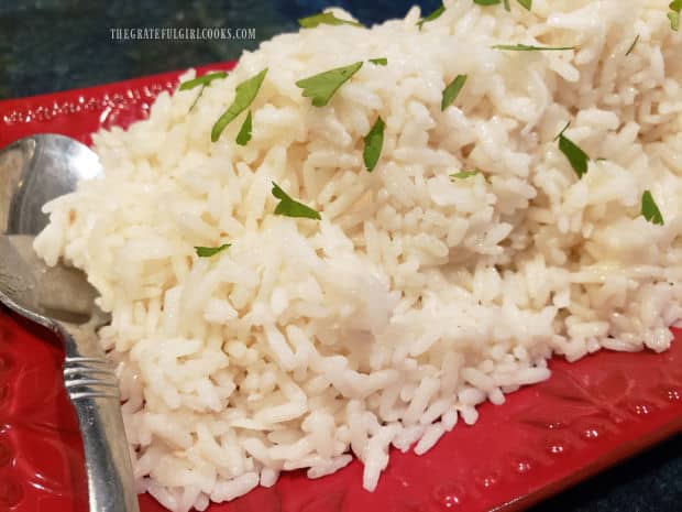Serving platter is piled high with creamy coconut rice and a spoon, for serving.