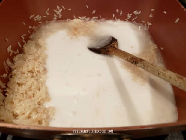 Stirring the canned coconut milk into the jasmine rice for more cooking.